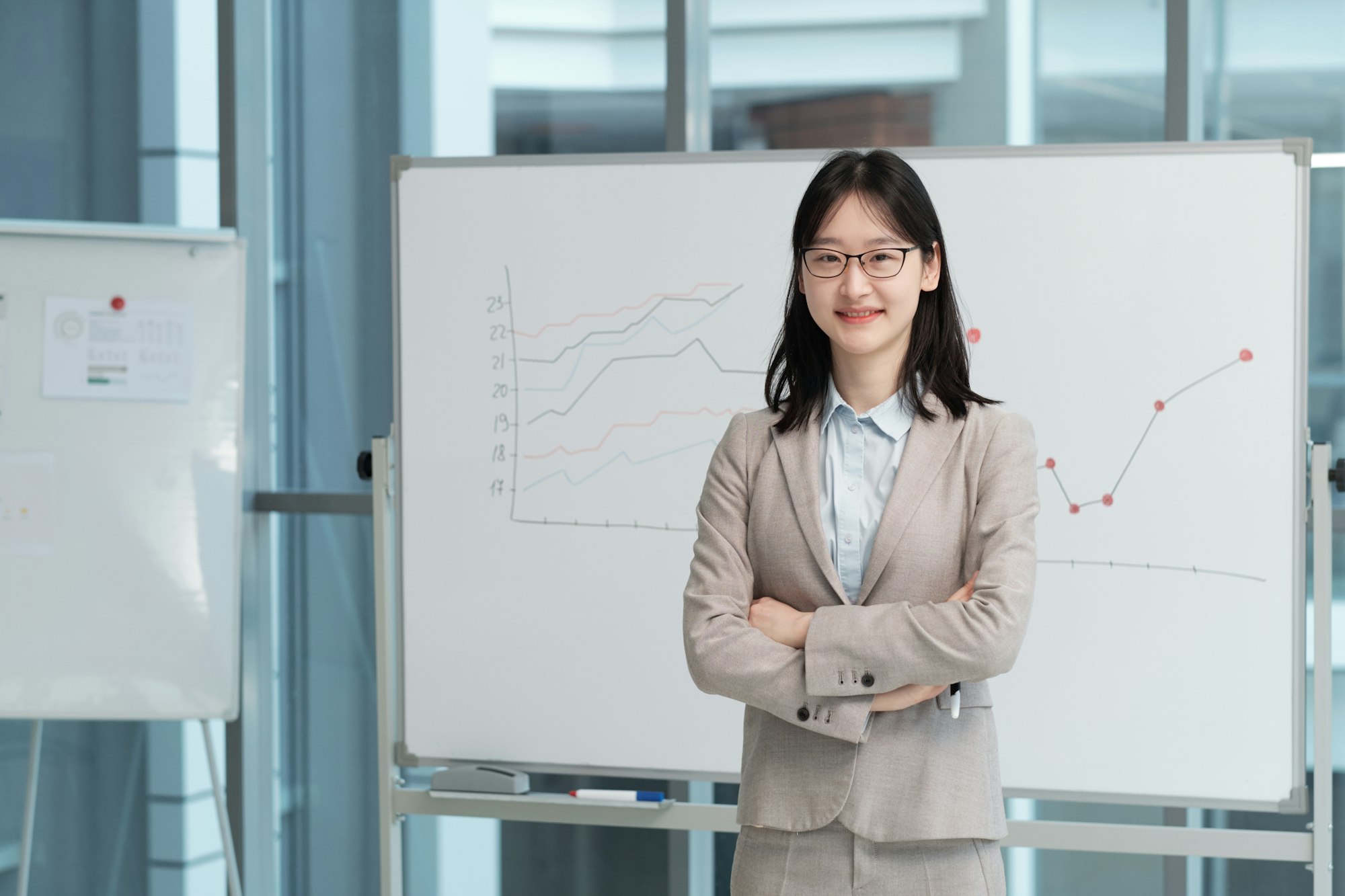 Young smiling female lecturer in formalwear and eyeglasses looking at camera